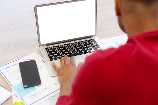 A close-up of a Venezuelan entrepreneur's hands filling out an online SENIAT registration form on a laptop, with a blurred background of their office and documents.