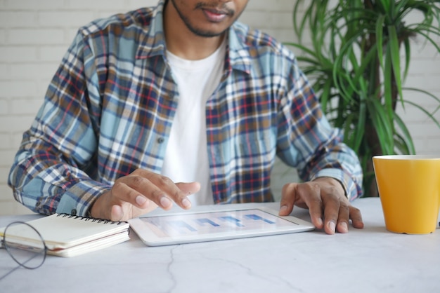 A Venezuelan business owner reviewing performance metrics on a tablet with a focused expression, highlighting data analysis and strategic planning, with a cityscape of Caracas in the background visible through the office window.