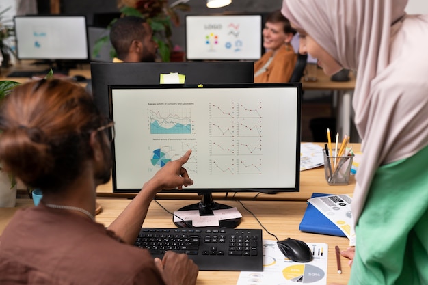 A diverse team in Venezuela using project management software on a large screen, with graphs showing improved efficiency and task completion rates, emphasizing the impact of technology on their work dynamic.