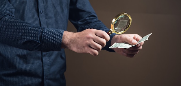 A person carefully checking the official registry of financial institutions in Venezuela on the Sudeban website. They are using a magnifying glass to scrutinize the details.