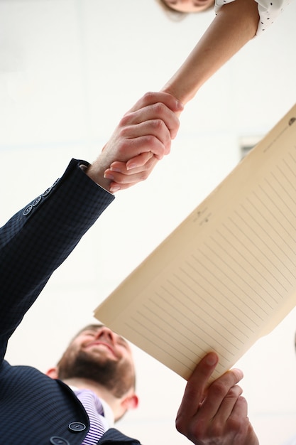 A close-up of two hands shaking over a document, symbolizing a negotiated agreement. The background is blurred, focusing attention on the hands and the document. The lighting is warm and professional, conveying trust and a successful negotiation.