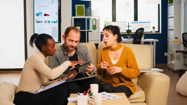 A visual representation of a Venezuelan family discussing investment options with a financial advisor, with charts and graphs suggesting potential growth and financial security displayed on a tablet screen.