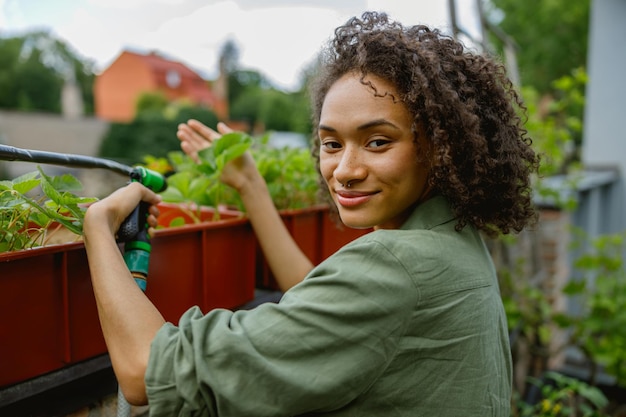 A Venezuelan woman watering her small, urban garden, demonstrating how to grow food sustainably in a city environment.